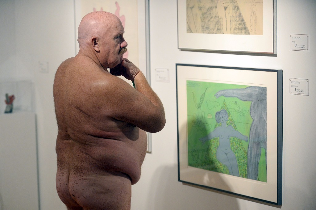 homme âgé nu regarde les toiles d'art