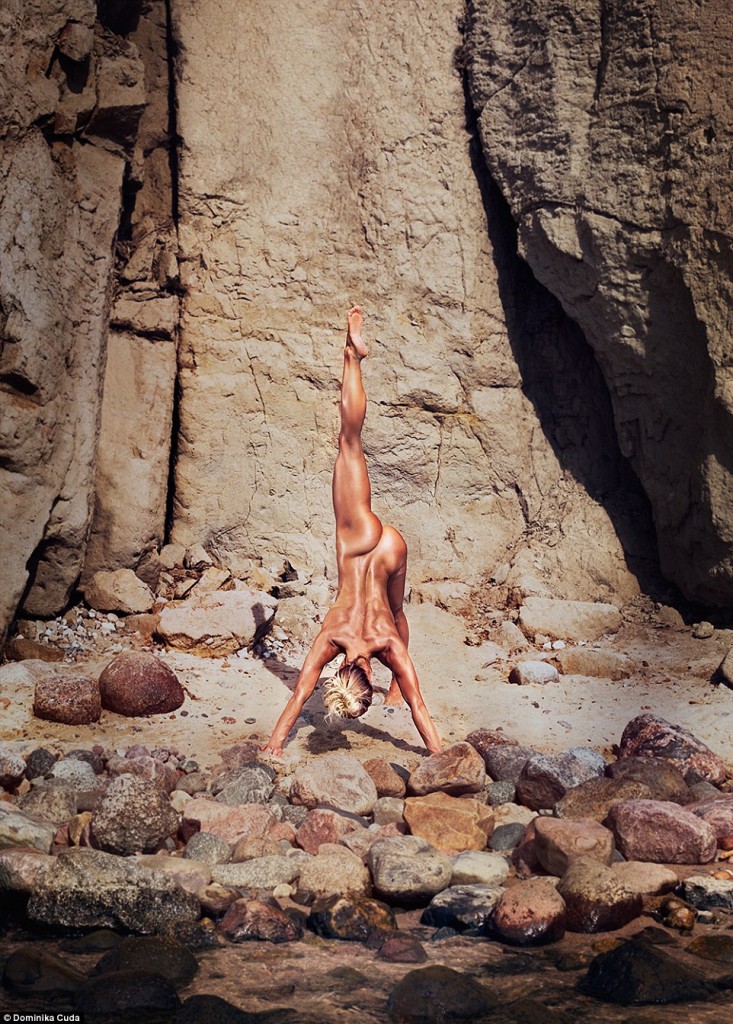 une blonde sportive nue pose corps renversé près du rocher